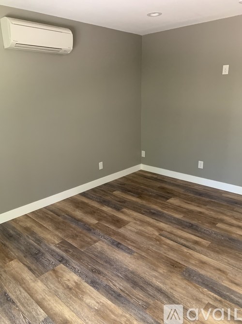 A room with a wooden floor and an air conditioner on the wall.