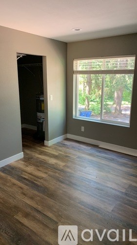 A room with wooden flooring and a window overlooking a garden.