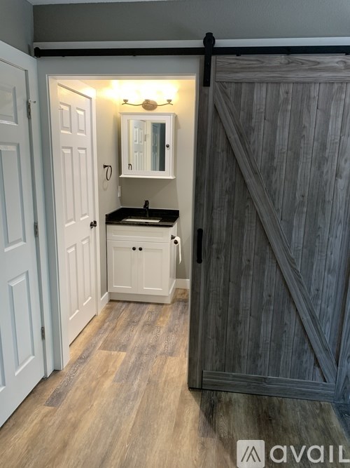 A bathroom with a wooden floor and a white cabinet with a mirror above it.