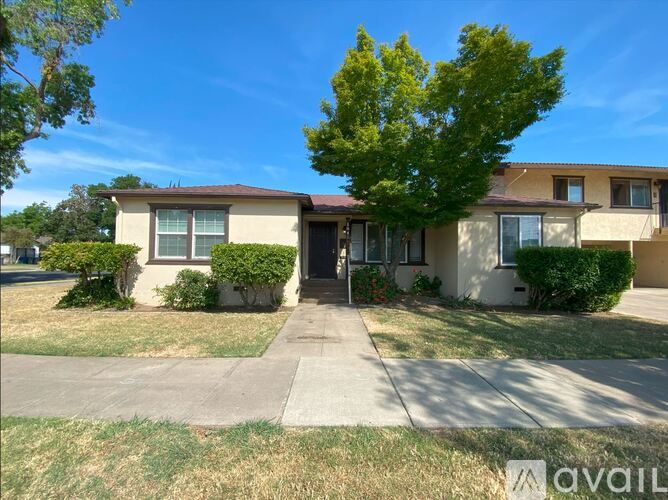 A house with a front yard and a tree in front.