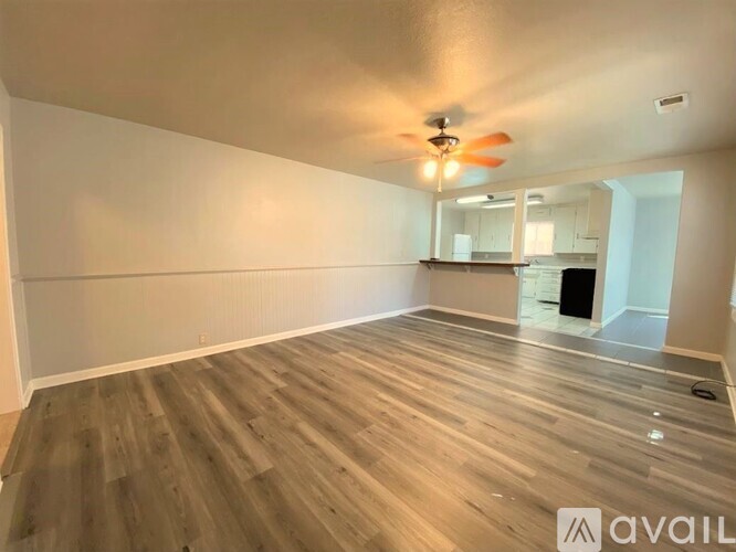 A spacious room with wooden flooring and a ceiling fan.
