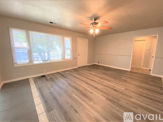 A spacious room with wooden flooring and a ceiling fan.