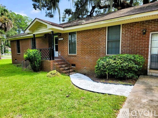 A small red brick house with a white roof and a small front yard.