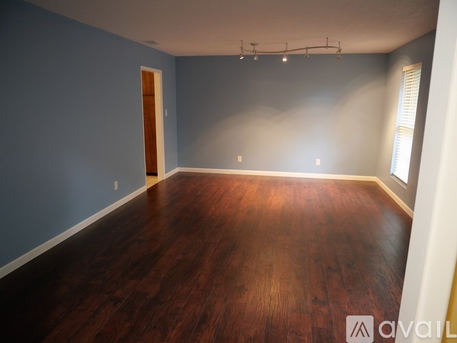 A room with wooden floors and a door on the left side.