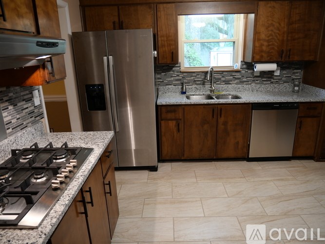 A kitchen with a stainless steel refrigerator, a stove top, and a sink.