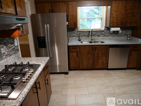 A kitchen with a stainless steel refrigerator, a stove top, and a sink.