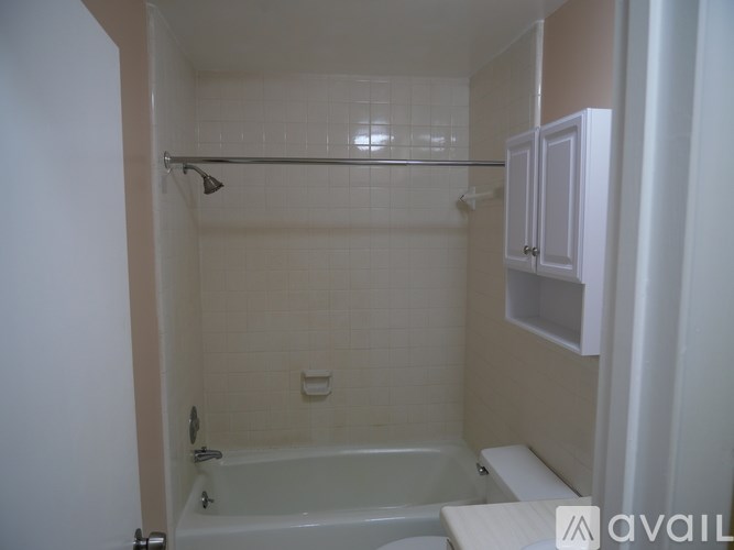 A bathroom with a white tub and shower, a white towel bar, and a white cabinet.