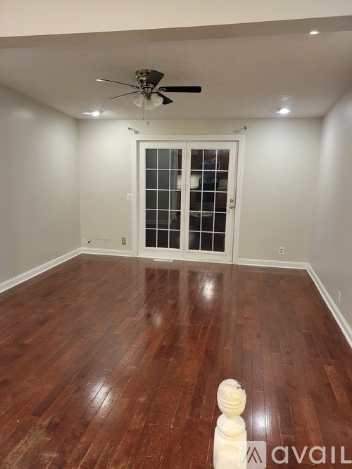 A room with a ceiling fan and wooden flooring.