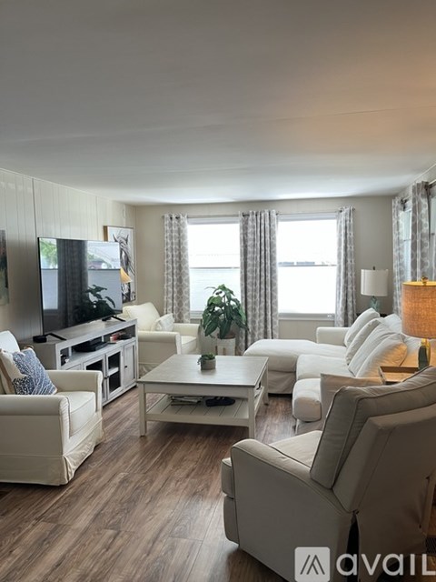A living room with white furniture and a flat screen TV.