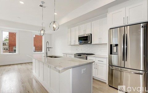A modern kitchen with a stainless steel refrigerator and white cabinets.