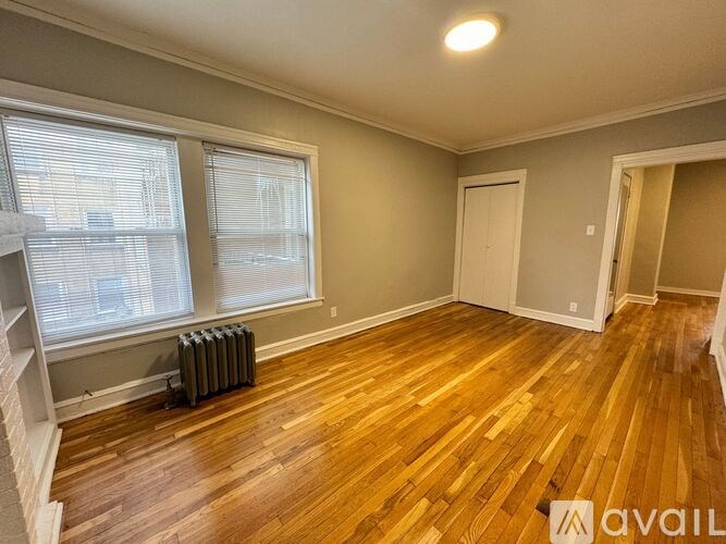 A room with wooden floors and a window with blinds.
