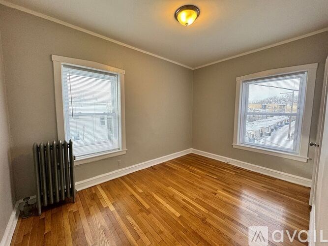 A room with wooden floors and two windows.