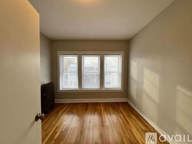 A room with a wooden floor and a window with blinds.
