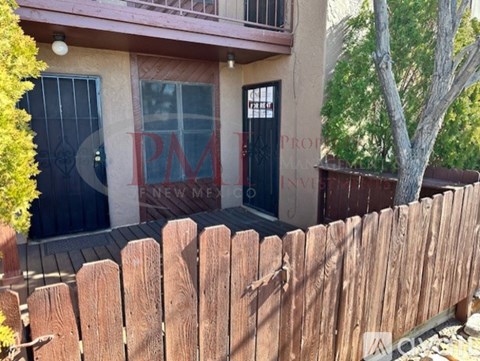 A wooden fence in front of a house with a sign that says "PM".
