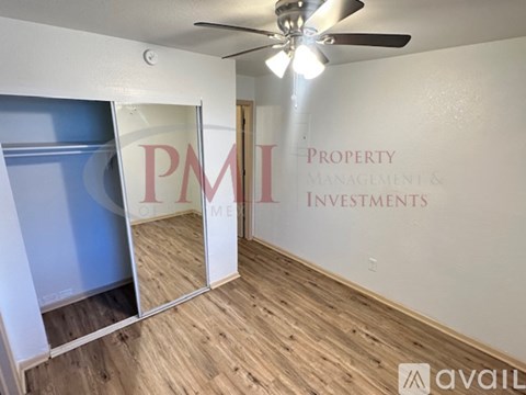 A room with a ceiling fan and a wall with "PMI Property Management & Investments" written on it.