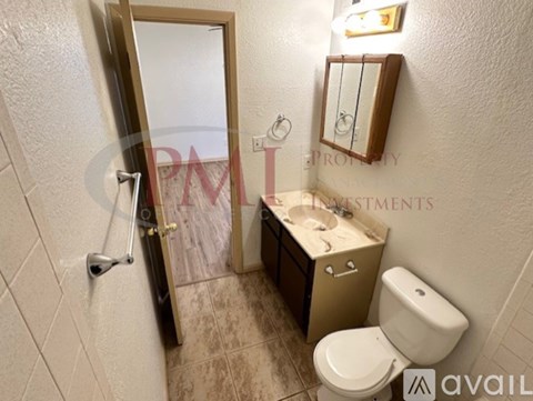 A bathroom with a toilet, sink, and mirror.