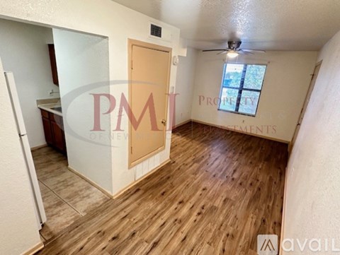 A room with wooden flooring and a door leading to another room.