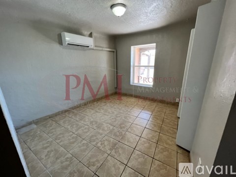 A room with beige tiled flooring and a window letting in natural light.