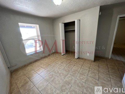 A room with beige tiled flooring and a doorway leading to another room.