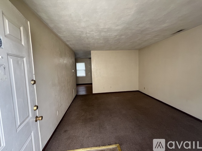 A room with a white door and carpeted floor.