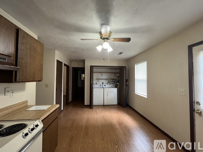A kitchen with a stove, a fan, and a washing machine.