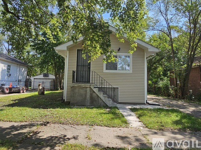 A small house with a metal gate and a window is surrounded by trees.