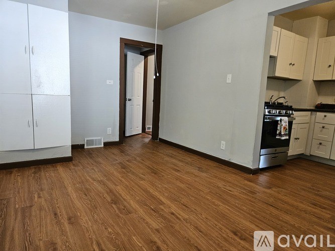 A kitchen with white cabinets and a wooden floor.