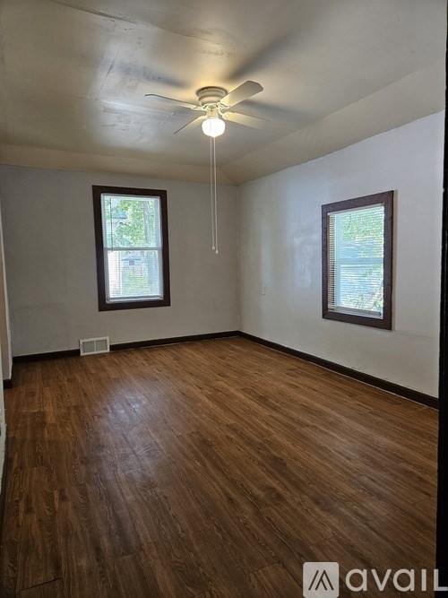 A room with wooden flooring and a ceiling fan.