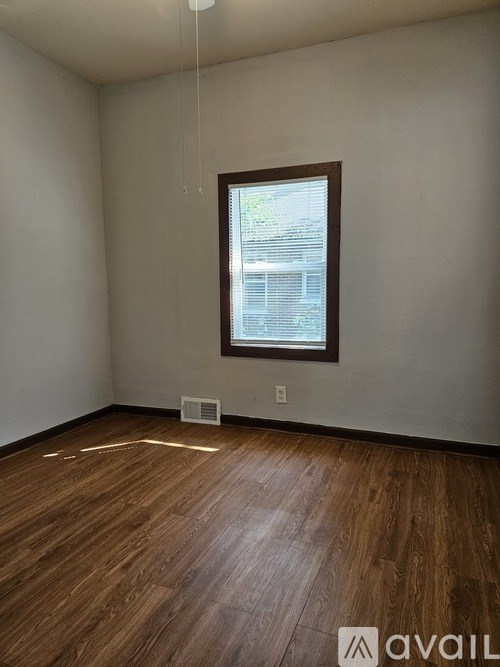 A room with wooden flooring and a window.