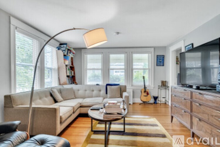 A living room with a white couch, a coffee table, a guitar, and a television.