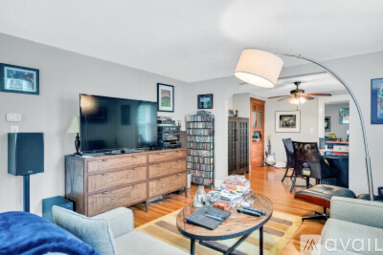 A living room with a television, a sofa, a coffee table, and a bookshelf.