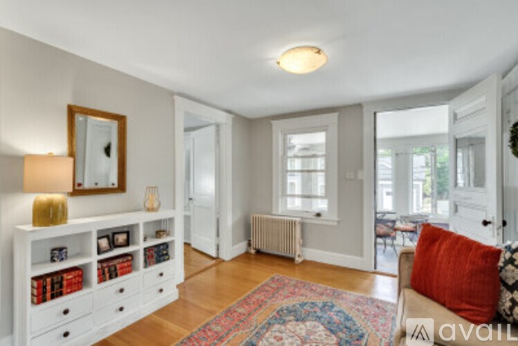 A living room with a white couch and a rug on the floor.