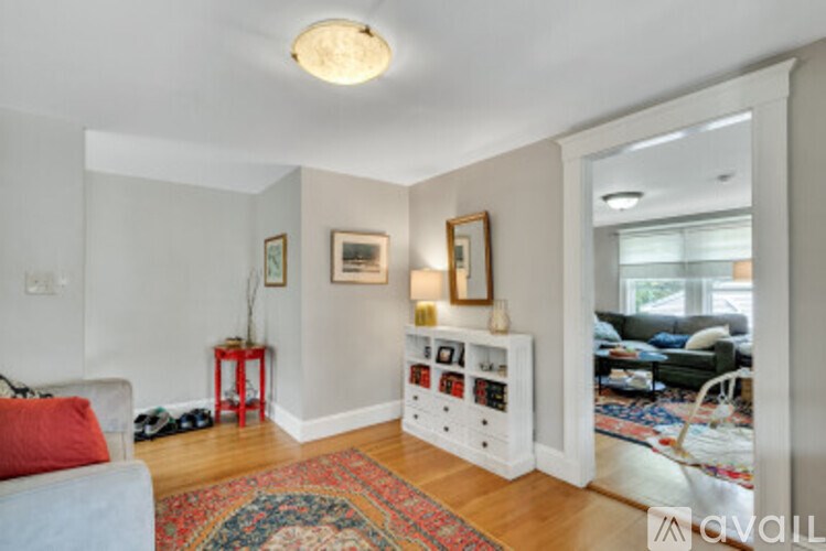 A living room with a white couch and a rug on the floor.