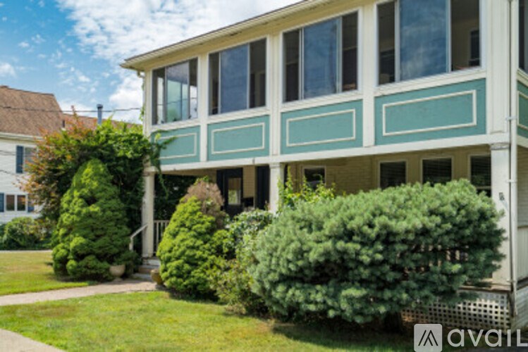 A house with a green lawn and bushes in front.