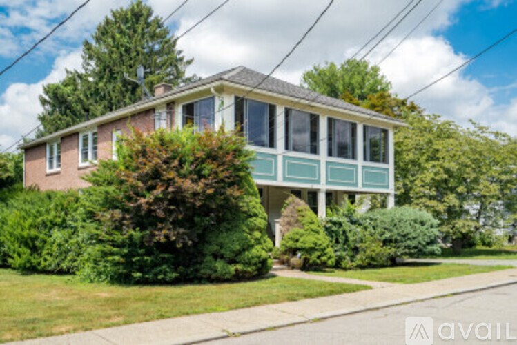 A house with a green porch and a tree in front.