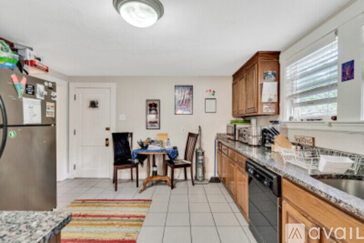 A kitchen with a refrigerator, sink, and a dining table with chairs.