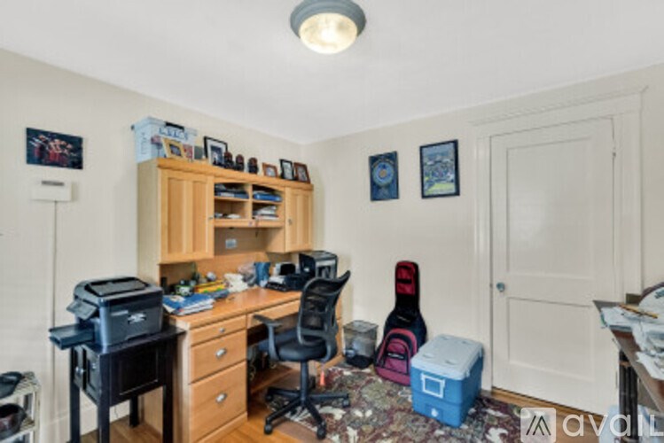 A small office with a desk, chair, and a guitar case.