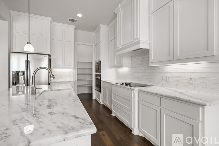 A kitchen with white cabinets and marble countertops.