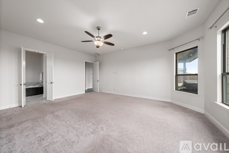 A spacious room with a ceiling fan and carpeted floor.
