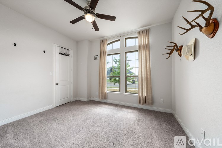 A room with a ceiling fan and deer head wall decorations.