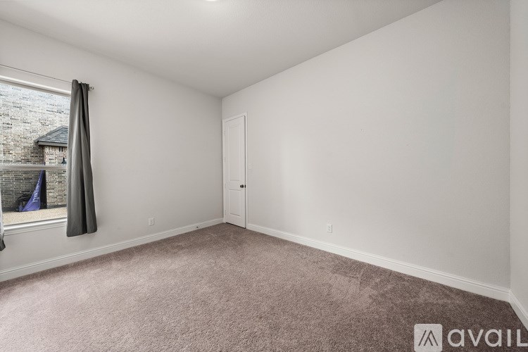 A room with a carpeted floor and a window with a view of a building outside.