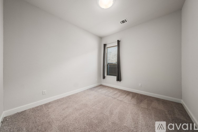 A room with a carpeted floor and a window with blinds.