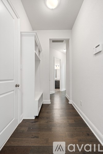 A long hallway with white walls and wood floors.