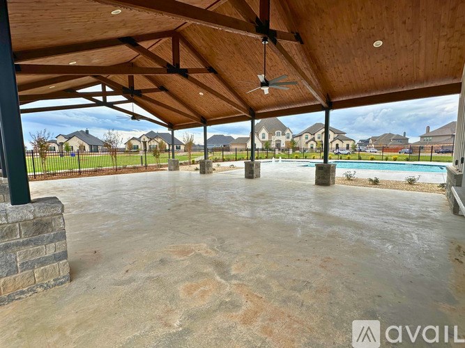 A covered patio area with a ceiling fan and a pool in the background.