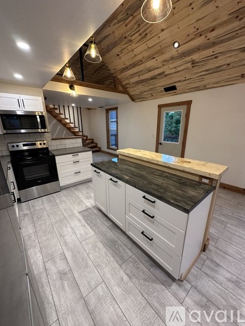 A kitchen with a wooden ceiling and a black stove top oven.