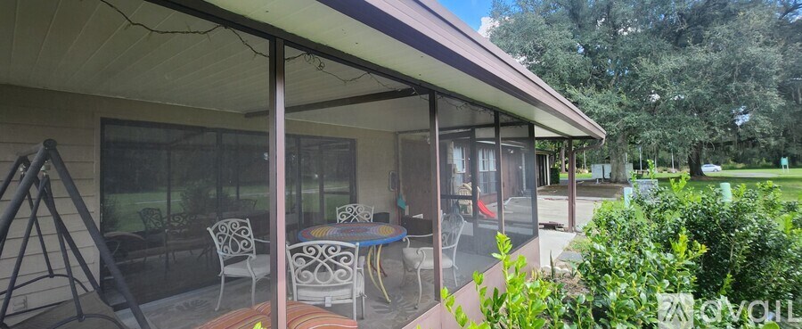 A patio with a table and chairs is covered by a glass roof.