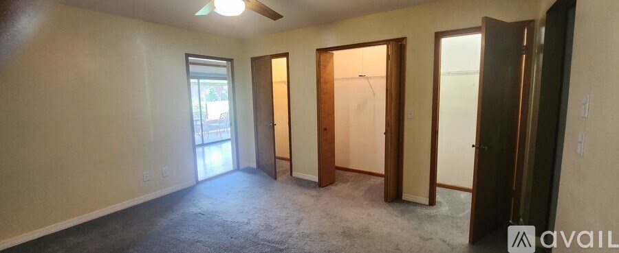 A room with a carpeted floor and a ceiling fan.