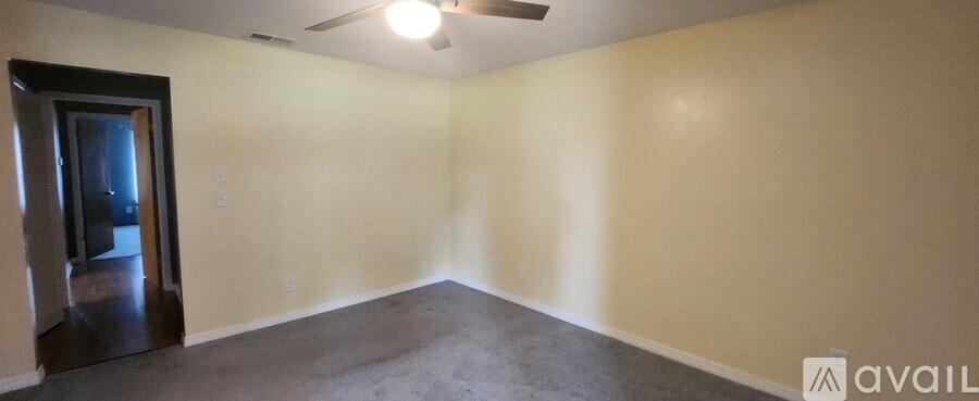 A room with a ceiling fan and a door on the left side.