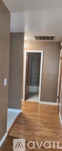 A room with wooden flooring and a doorway leading to another room.