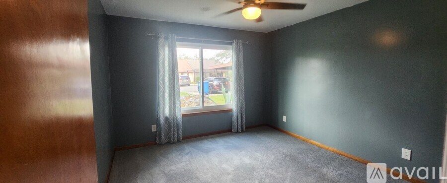 A room with a ceiling fan and a window with curtains.